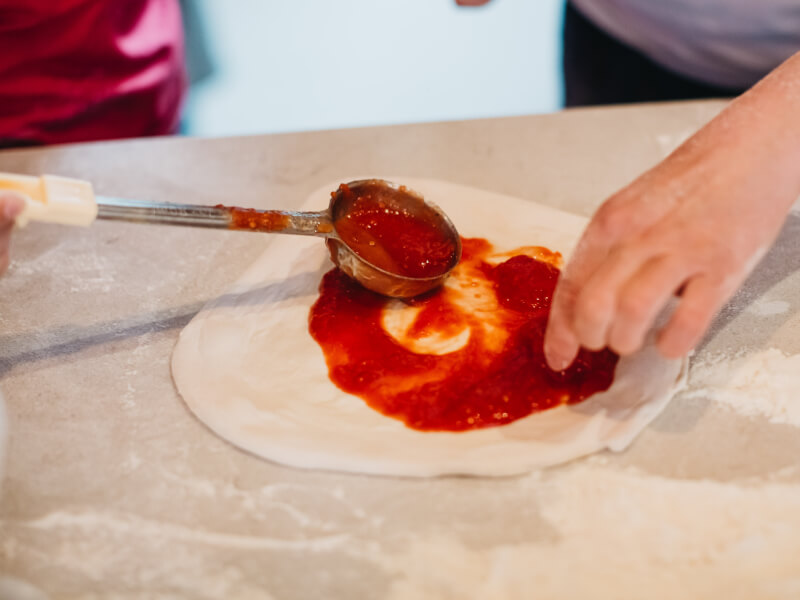 pouring sauce on pizza
